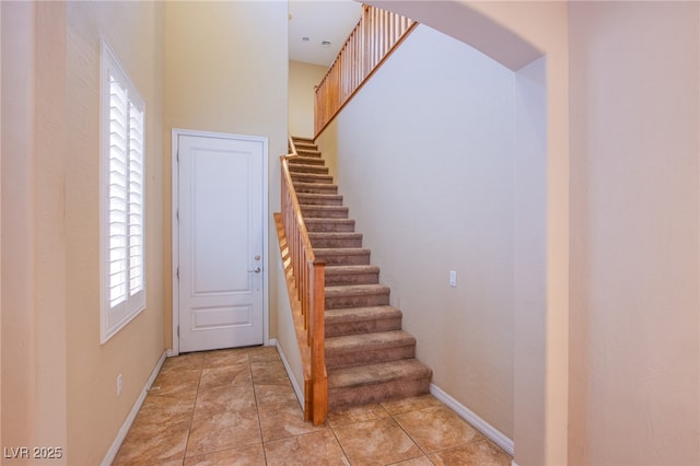 stairs featuring baseboards and a high ceiling