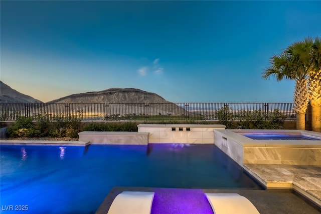 2910 Raywood Ash Dr, Las Vegas, NV 89138 - pool at dusk with a fenced in pool, a fenced backyard, an in ground hot tub, and a mountain view