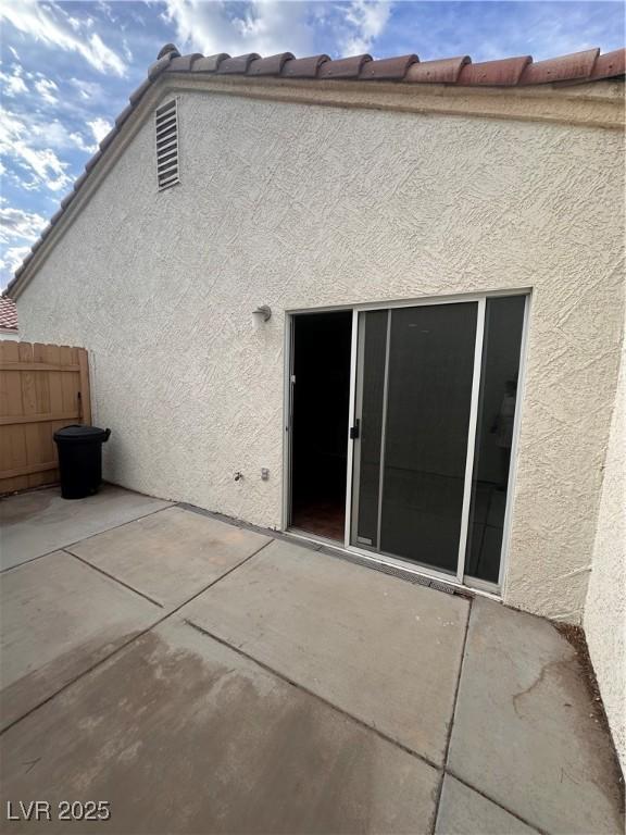 rear view of property featuring a patio, stucco siding, and fence