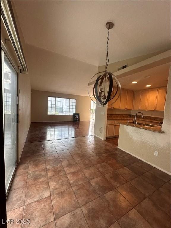 unfurnished dining area featuring an inviting chandelier, a sink, visible vents, and baseboards