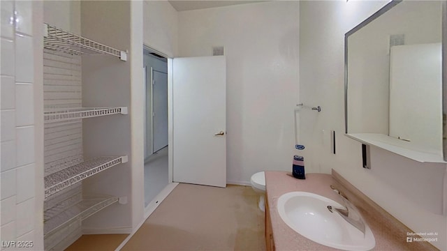 bathroom featuring toilet, vanity, visible vents, and baseboards