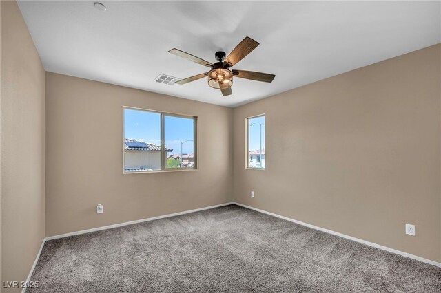 empty room with visible vents, carpet flooring, baseboards, and ceiling fan