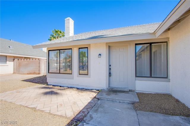 3118 Floral Vista Ave, Henderson, NV 89014 - view of exterior entry featuring stucco siding, roof with shingles, a chimney, and a patio