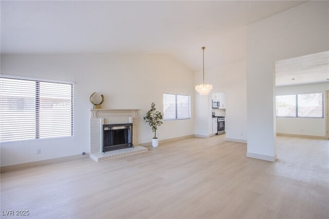 3118 Floral Vista Ave, Henderson, NV 89014 - unfurnished living room featuring lofted ceiling, baseboards, a chandelier, light wood-style flooring, and a brick fireplace