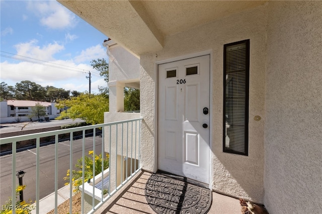 entrance to property featuring a balcony and stucco siding