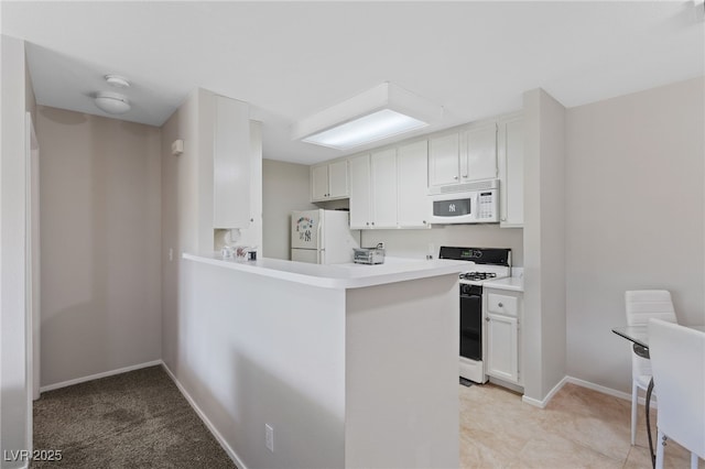 kitchen featuring light countertops, white cabinets, baseboards, and white appliances