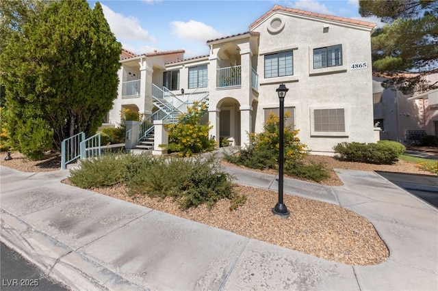 mediterranean / spanish-style home featuring stucco siding, a tiled roof, and stairway