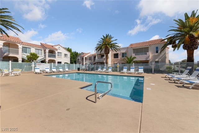 community pool with fence, a residential view, and a patio