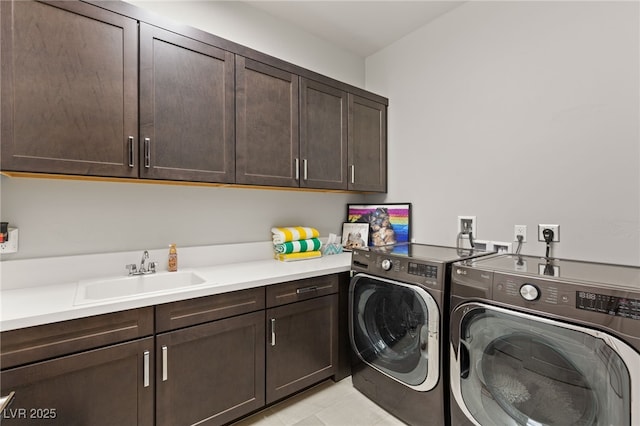 washroom with washing machine and clothes dryer, cabinet space, and a sink