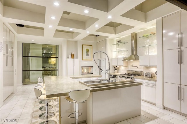 8525 W Verde Way, Las Vegas, NV 89149 - kitchen featuring wall chimney exhaust hood, range, modern cabinets, coffered ceiling, and white cabinetry