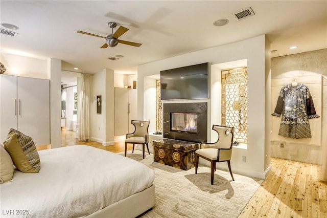 8525 W Verde Way, Las Vegas, NV 89149 - bedroom with a tile fireplace, light wood finished floors, connected bathroom, a ceiling fan, and recessed lighting