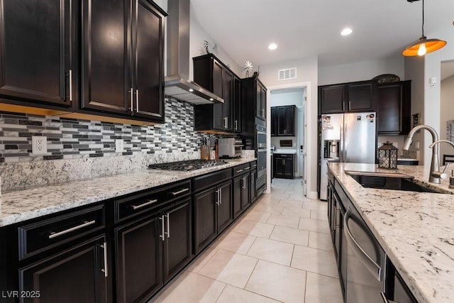 kitchen featuring wall chimney range hood, a sink, backsplash, appliances with stainless steel finishes, and visible vents