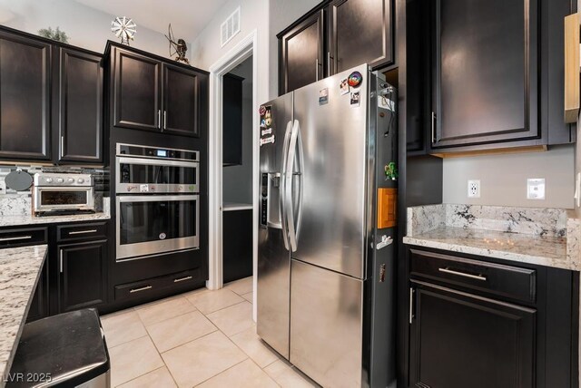 kitchen with light stone countertops, stainless steel appliances, visible vents, and light tile patterned floors