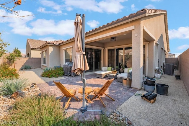 back of property featuring stucco siding, central AC unit, a patio, and a fenced backyard