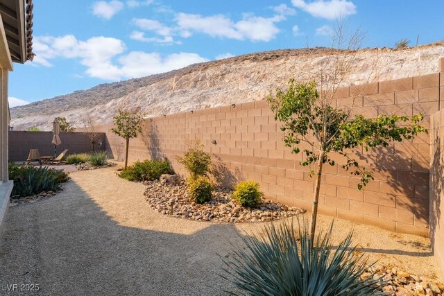 view of yard with a fenced backyard, a mountain view, and a patio