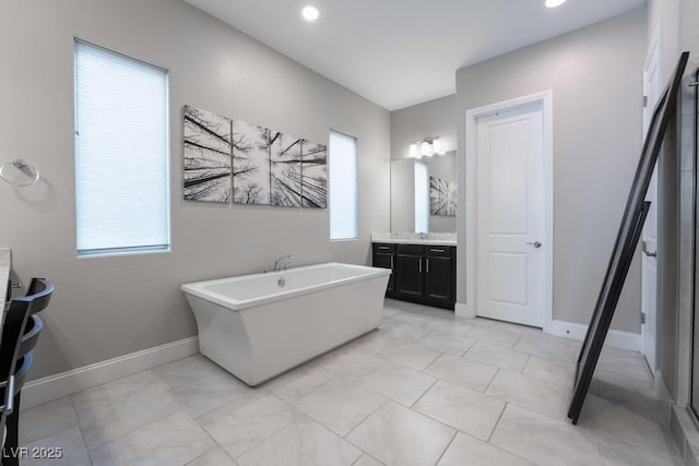 full bath with a freestanding bath, baseboards, and vanity