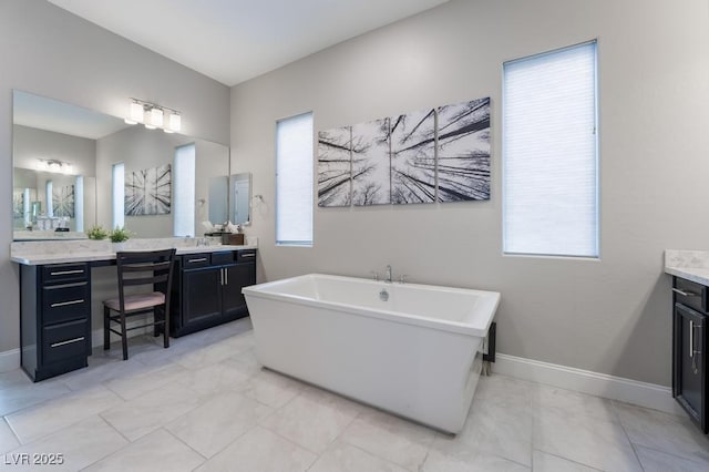 full bath featuring baseboards, vanity, and a freestanding bath
