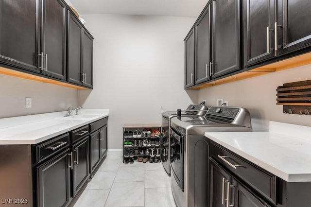 laundry area with a sink, light tile patterned floors, cabinet space, baseboards, and independent washer and dryer