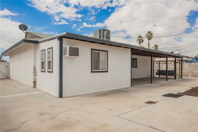 view of property exterior featuring fence, an AC wall unit, a patio area, and central AC unit