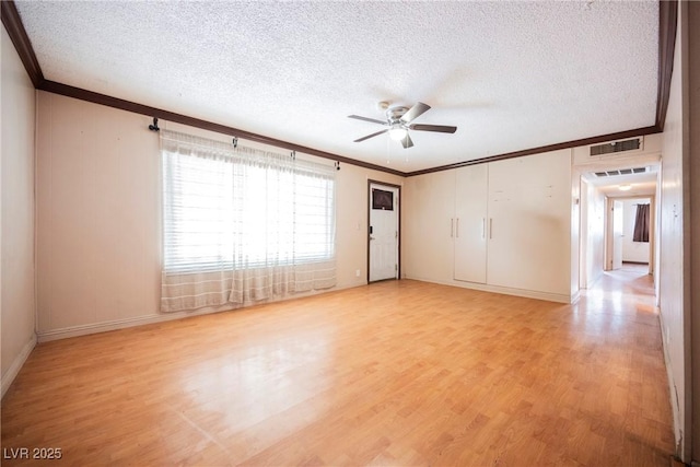 unfurnished room with visible vents, ornamental molding, light wood-style floors, a textured ceiling, and ceiling fan