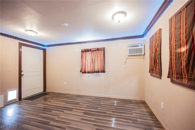 interior space featuring a wall mounted air conditioner, baseboards, crown molding, and wood finished floors
