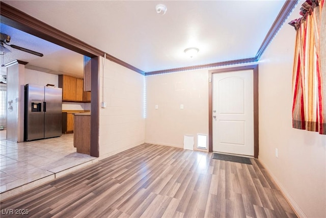 unfurnished living room with light wood-style flooring, baseboards, ceiling fan, and crown molding
