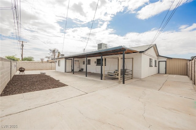 rear view of house featuring a fenced backyard, central AC unit, and a patio