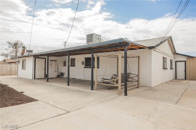 back of house featuring central AC, fence, concrete block siding, and a patio area
