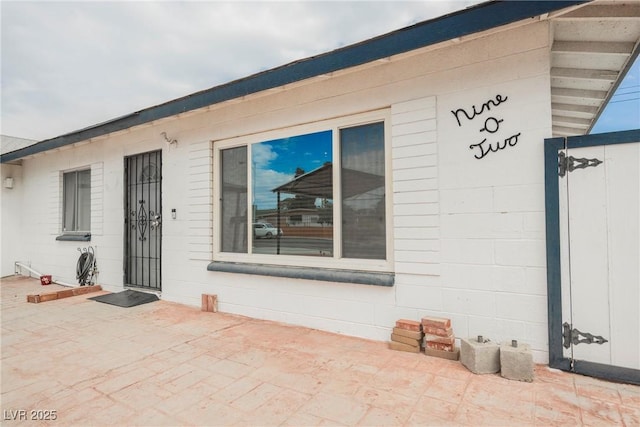 doorway to property with concrete block siding and a patio