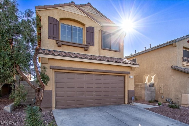 mediterranean / spanish-style home with stucco siding, an attached garage, a tiled roof, and concrete driveway
