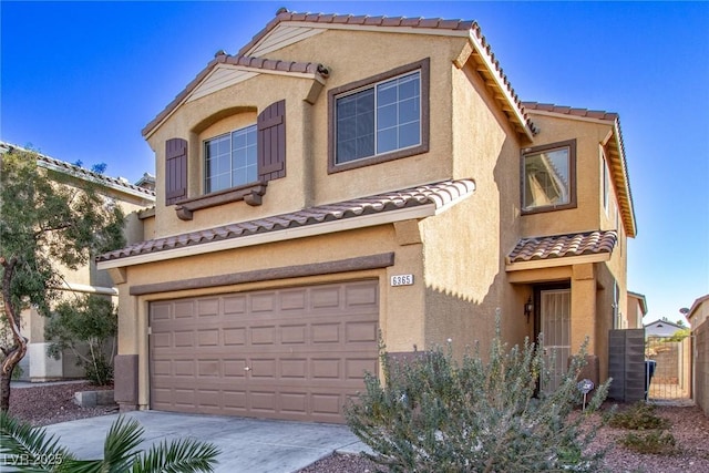mediterranean / spanish-style house with a tile roof, driveway, fence, a garage, and stucco siding