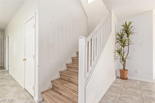 stairway with baseboards and tile patterned flooring