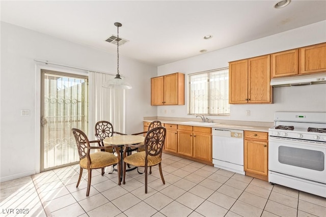 kitchen featuring plenty of natural light, under cabinet range hood, light countertops, a sink, and white appliances
