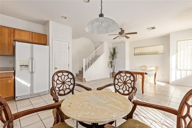 dining space with stairway, ceiling fan, visible vents, and light tile patterned floors