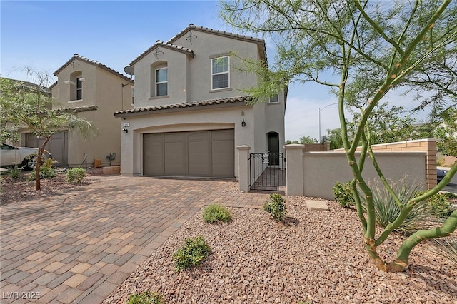 mediterranean / spanish home with a tile roof, a gate, an attached garage, stucco siding, and decorative driveway