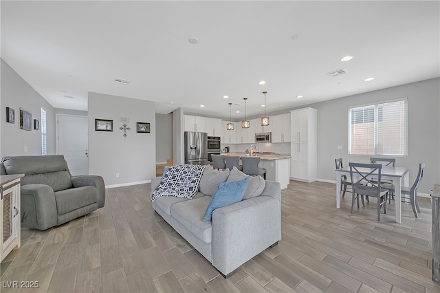 living room featuring wood finish floors, visible vents, and baseboards