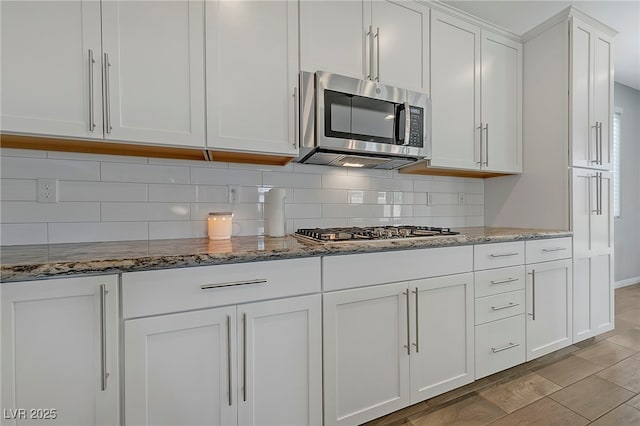 kitchen featuring white cabinets, stainless steel appliances, backsplash, and light stone counters