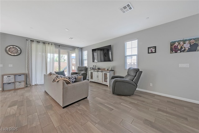 living area featuring visible vents, light wood finished floors, and baseboards