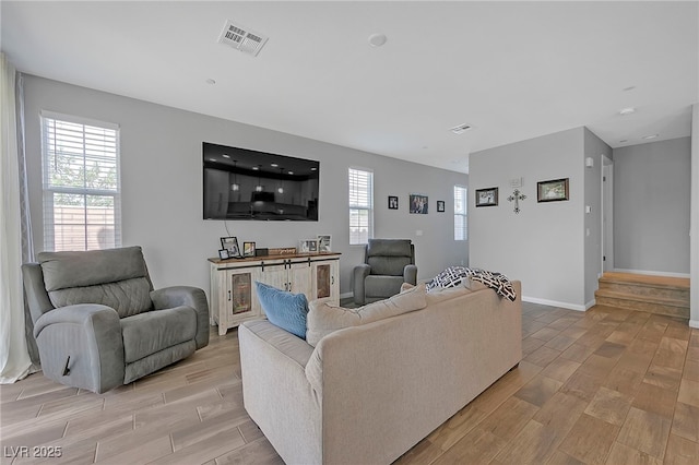 living area featuring light wood-type flooring, visible vents, and baseboards