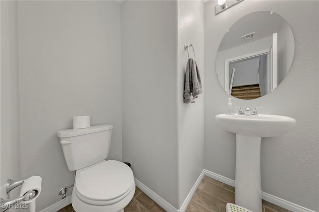 half bath with wood finished floors, visible vents, toilet, and baseboards