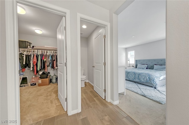 interior space featuring baseboards, light carpet, and light wood-style flooring