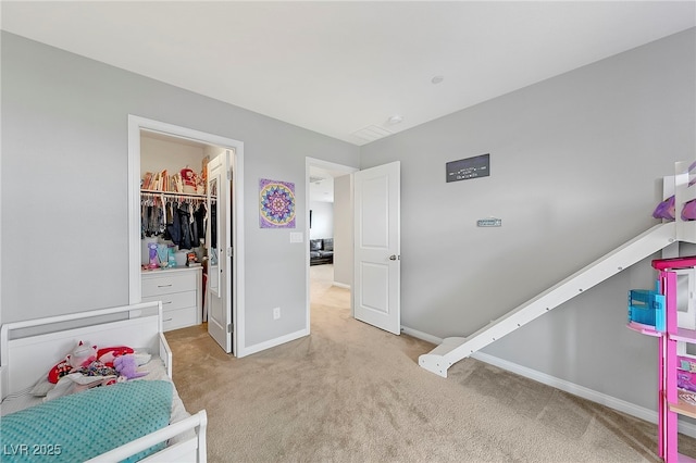 bedroom featuring a walk in closet, carpet floors, a closet, and baseboards