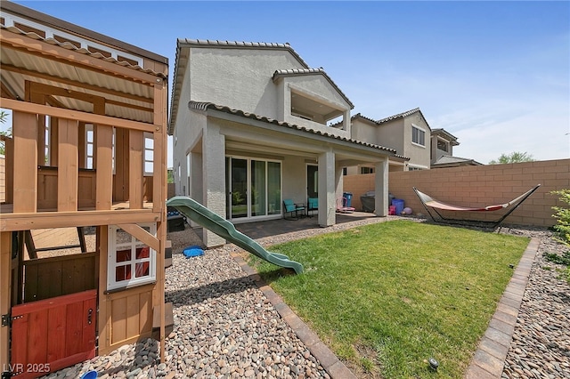 back of property with a lawn, a patio area, a fenced backyard, and stucco siding
