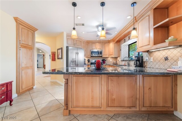 kitchen featuring appliances with stainless steel finishes, arched walkways, a peninsula, ceiling fan, and tasteful backsplash