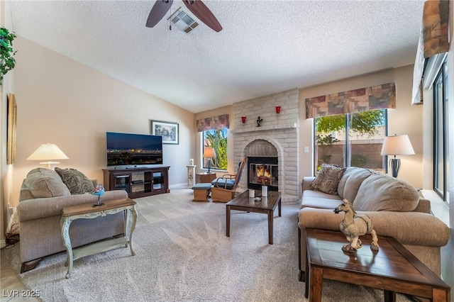 living room featuring a textured ceiling, plenty of natural light, a fireplace, light carpet, and ceiling fan