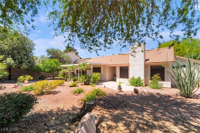 back of property with a tile roof, a chimney, stucco siding, a patio area, and fence