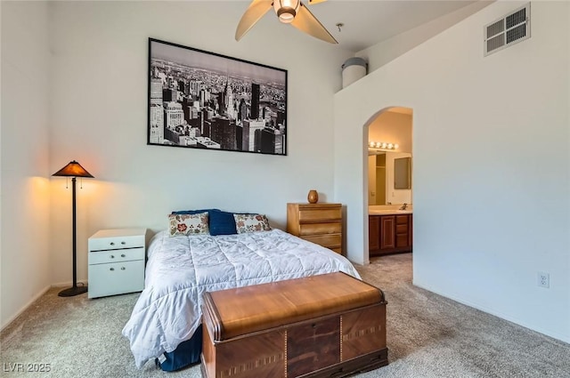 carpeted bedroom featuring a sink, ceiling fan, arched walkways, ensuite bath, and visible vents