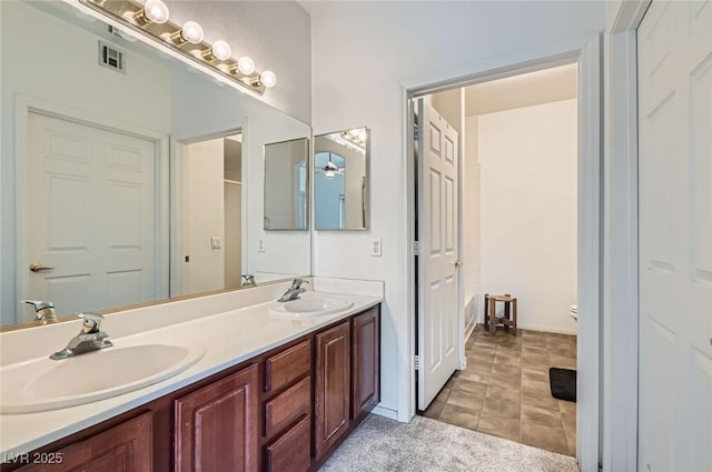 bathroom featuring double vanity, visible vents, toilet, and a sink