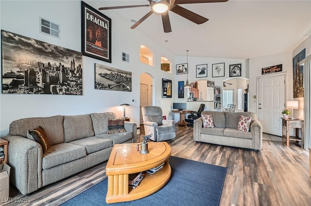 living area with arched walkways, wood finished floors, visible vents, and ceiling fan