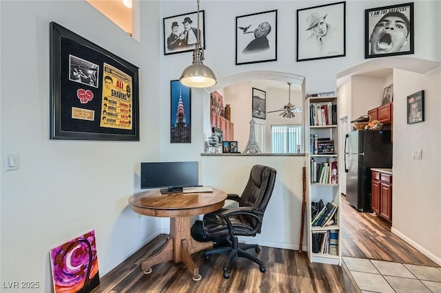 home office with arched walkways, baseboards, a ceiling fan, and wood finished floors